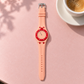 Vibe Blush peach watch with red bezel on a pink cafe table