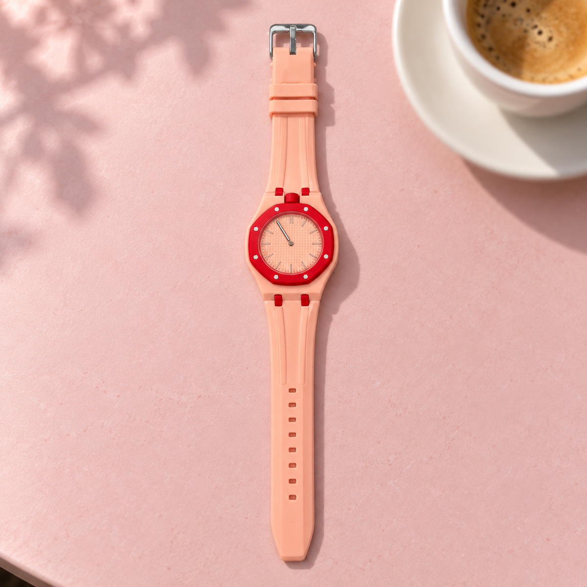 Vibe Blush peach watch with red bezel on a pink cafe table